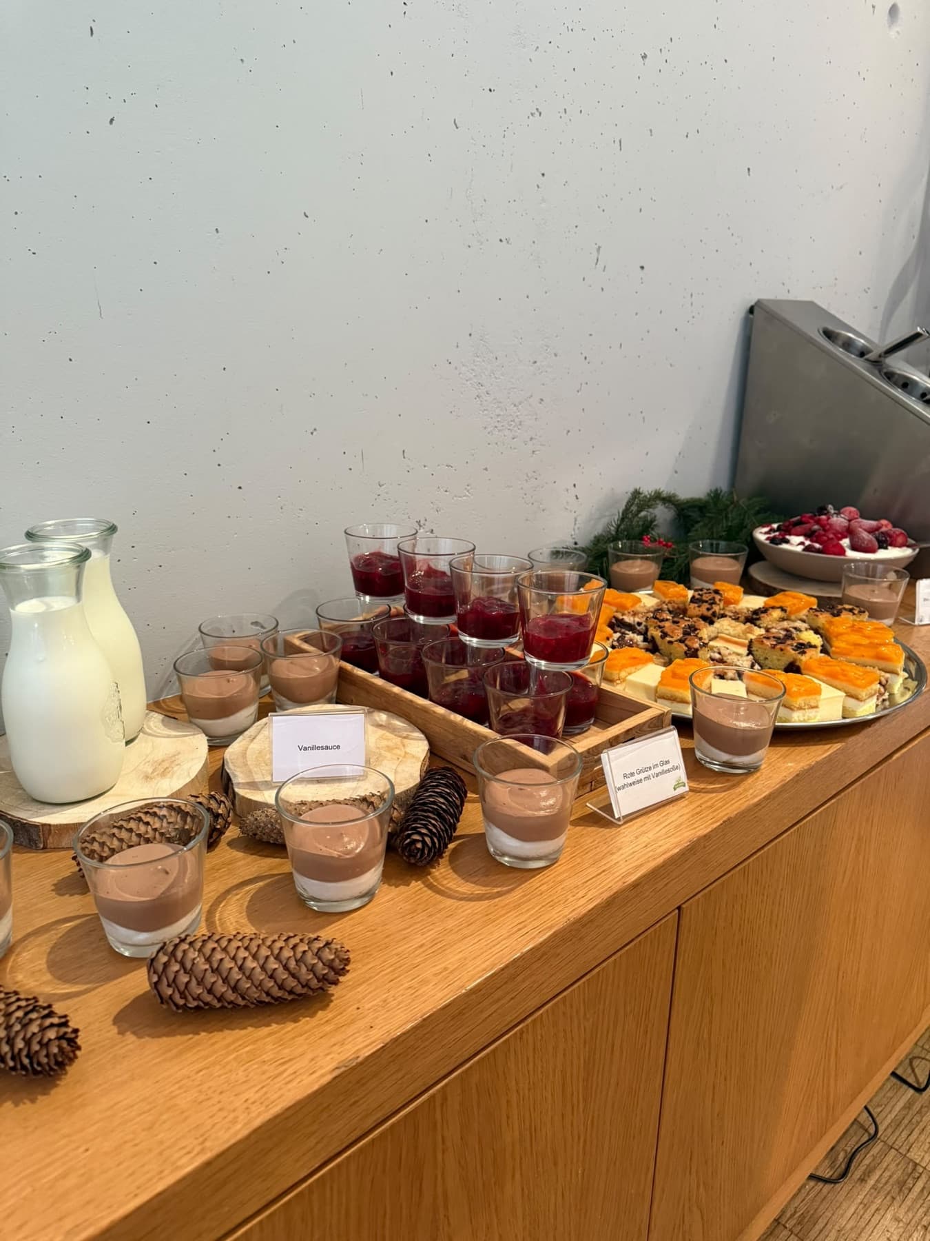 Brunch-Buffet an der langen Holztafel mit Brotkörben und Aufschnitt, winterlich dekoriert, dahinter die Fensterfront