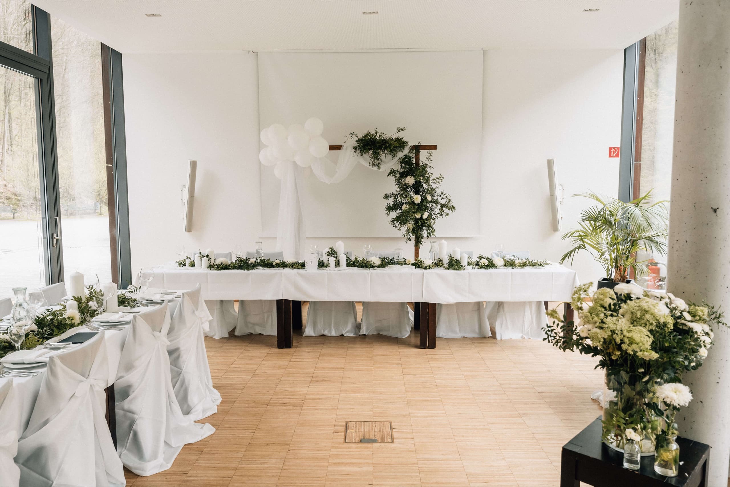 Brauttafel mit Blumendekoration und freier Tanzfläche im Saal