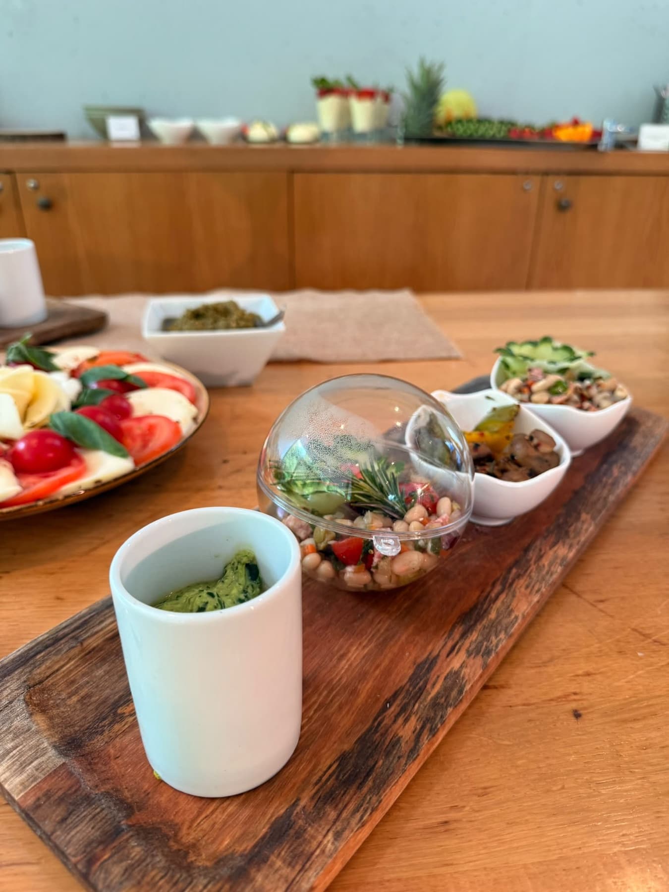 Holzbrett mit Antipasti, Salat und Dips, daneben Tomate-Mozzarella