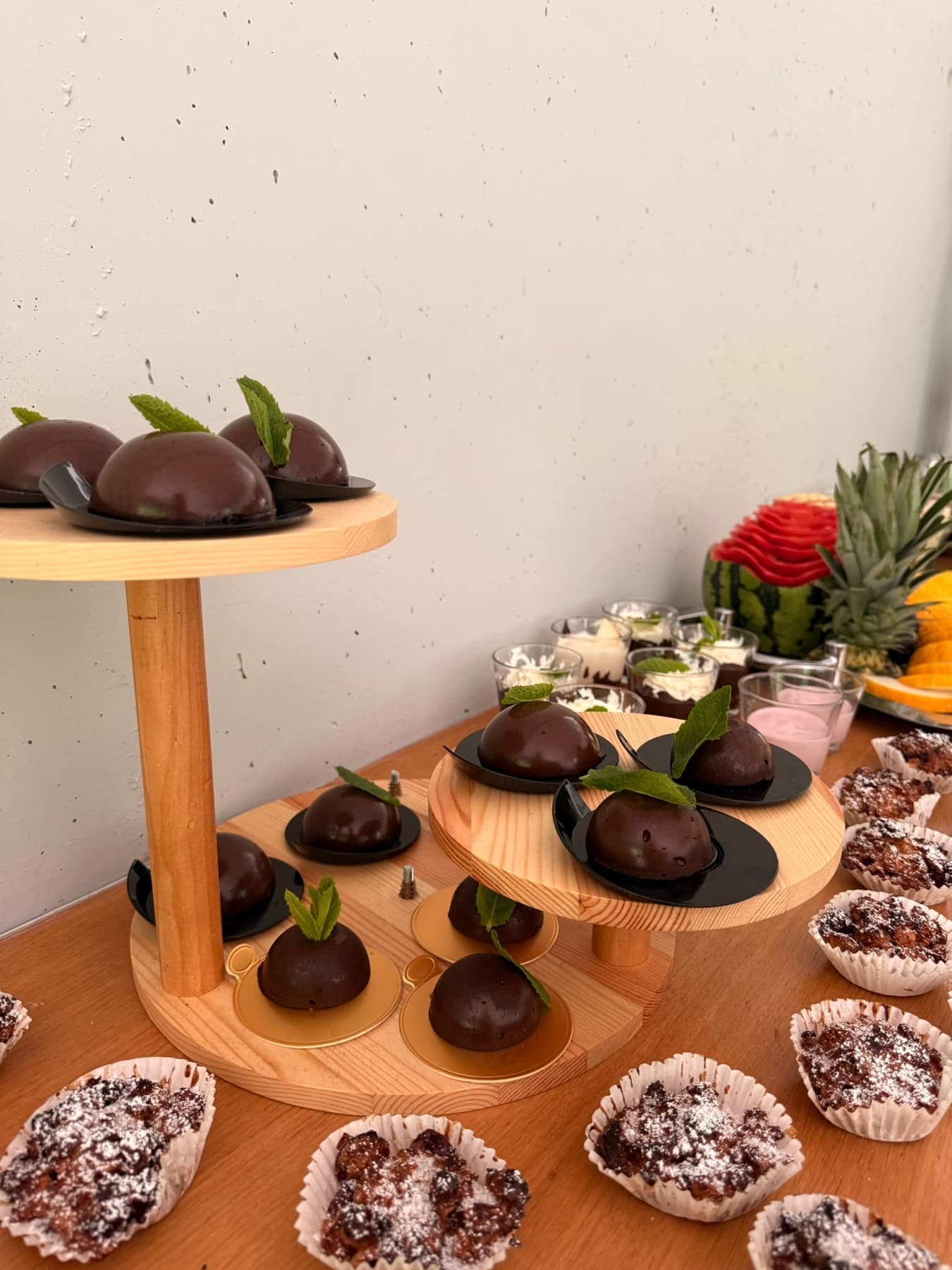 Süße Desserts auf hölzernen Etageren, davor Gebäck mit Puderzucker
