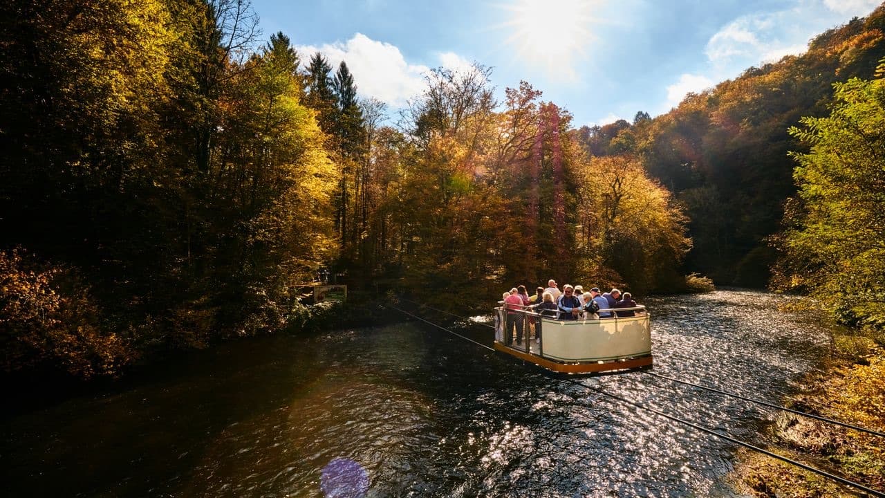 Die Schwebefähre überquert im Herbstlicht die Wupper, Gäste stehen an der Reling